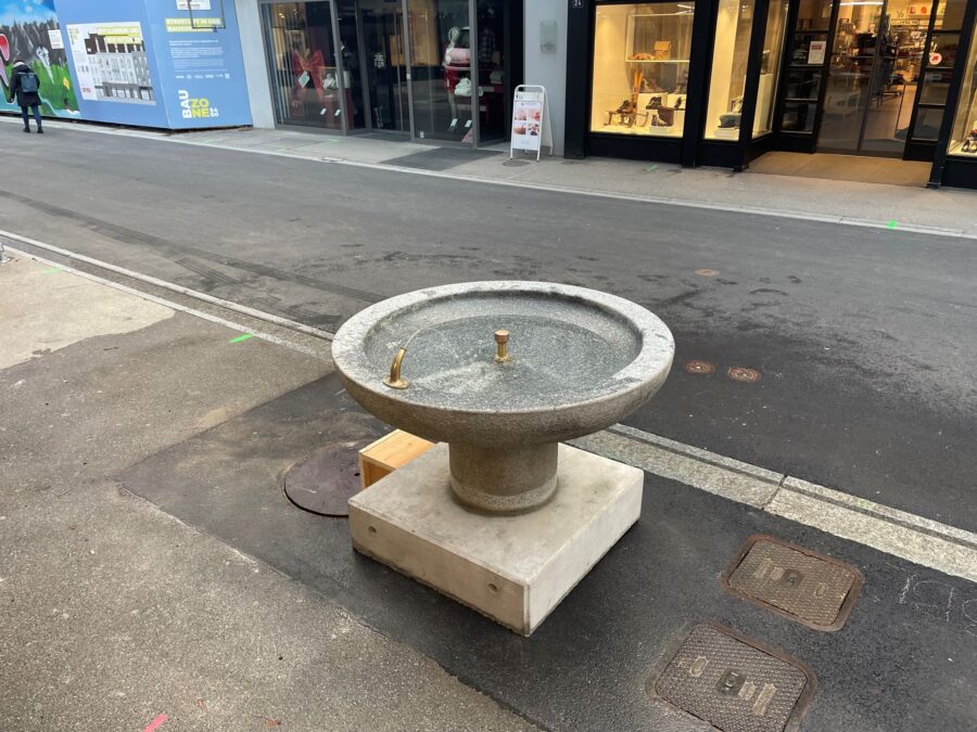 Der Brunnen ist auf einem provisorischen Sockel platziert und mit einem ebenfalls provisorischen Anschluss versehen